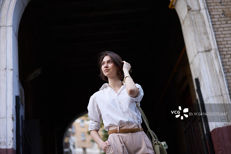 自信的年轻女性走过城市拱门图片素材