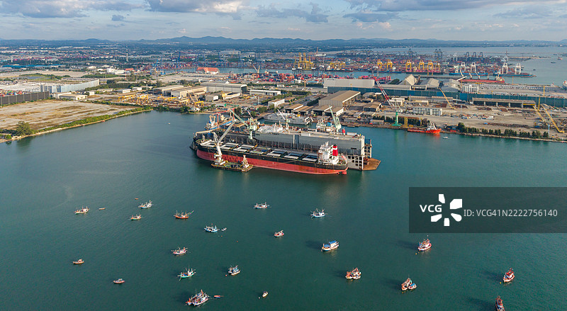 在船厂的浮动干船坞中，货船进行维护或修理，两个甲板起重机正在装载，将船只带入干船坞。图片素材