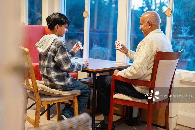 老年人与孙子（12-13岁）一起玩牌图片素材