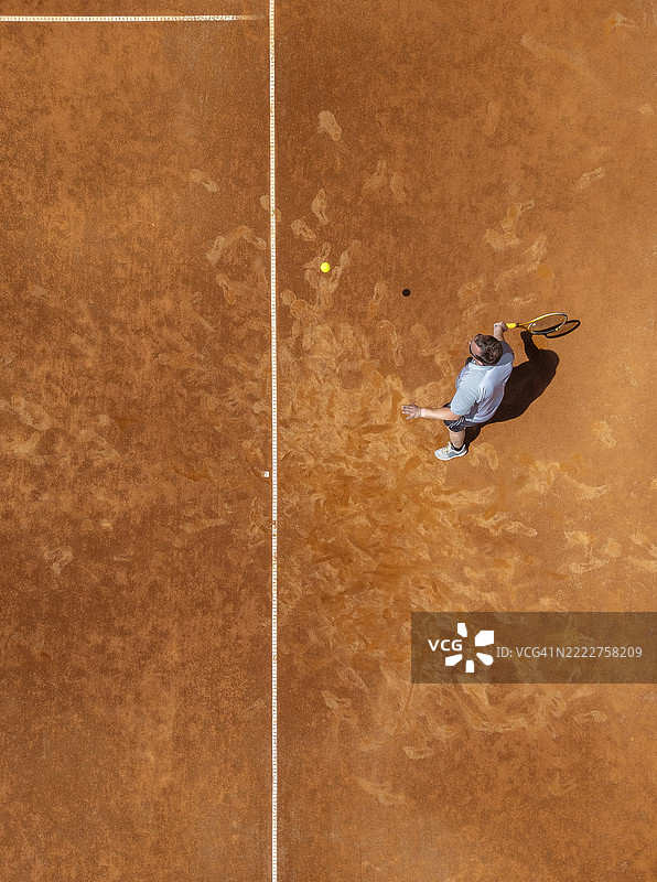 阳光照耀下的红土网球场上，网球运动员的俯视图图片素材