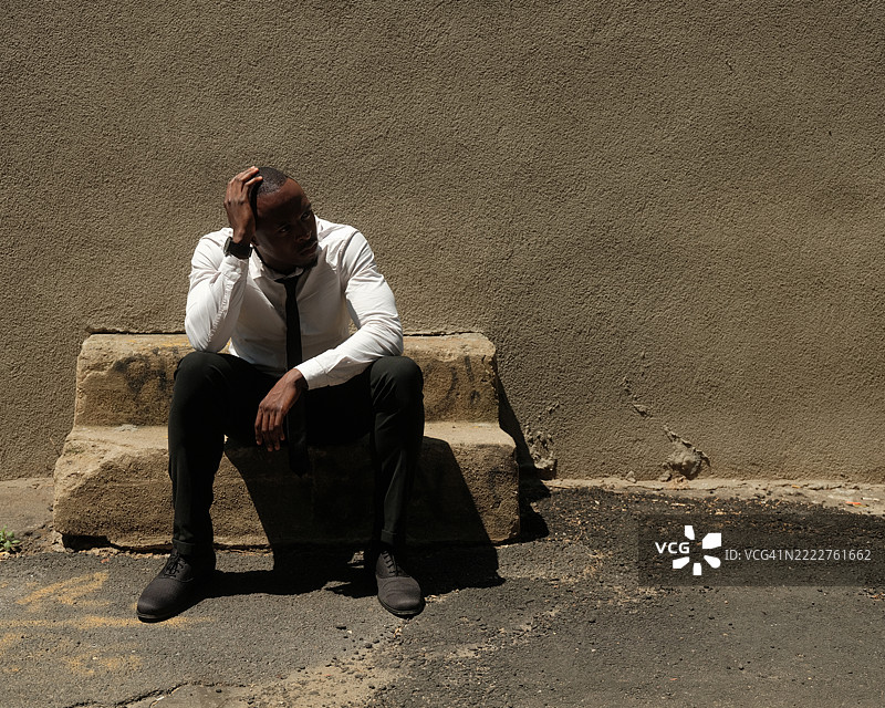 美国，纽约市，疲惫的商人坐在户外的旧石凳上图片素材