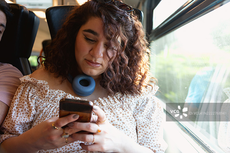 年轻女性坐在火车上看手机图片素材