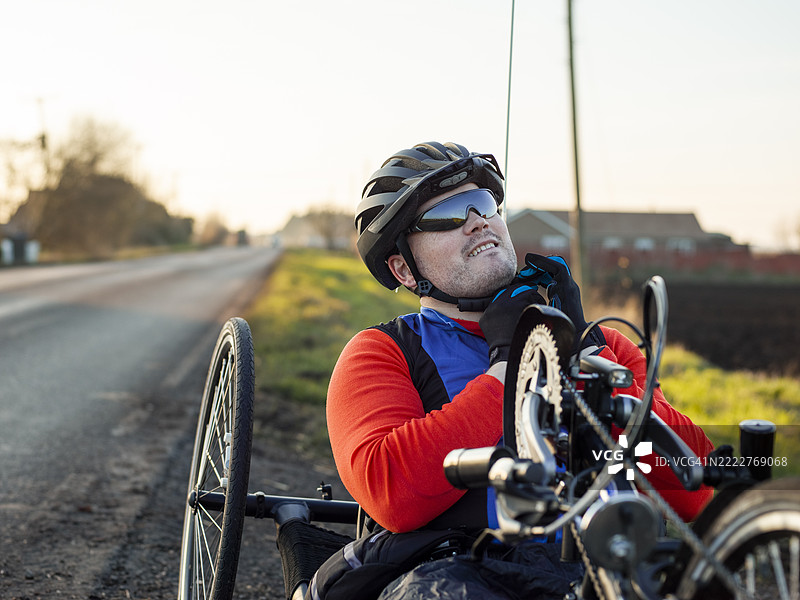 路边的残疾人正在手动自行车上系骑行头盔图片素材