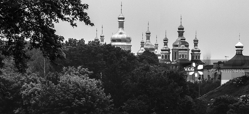 基辅佩乔尔斯克修道院的教堂圆顶在树木上方耸立，黑白色调。图片素材