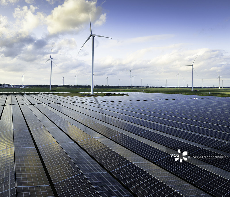 夏季傍晚从空中俯瞰的太阳能发电场和风力涡轮机图片素材