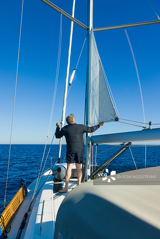船员在帆船上检查主帆的卷起情况图片素材