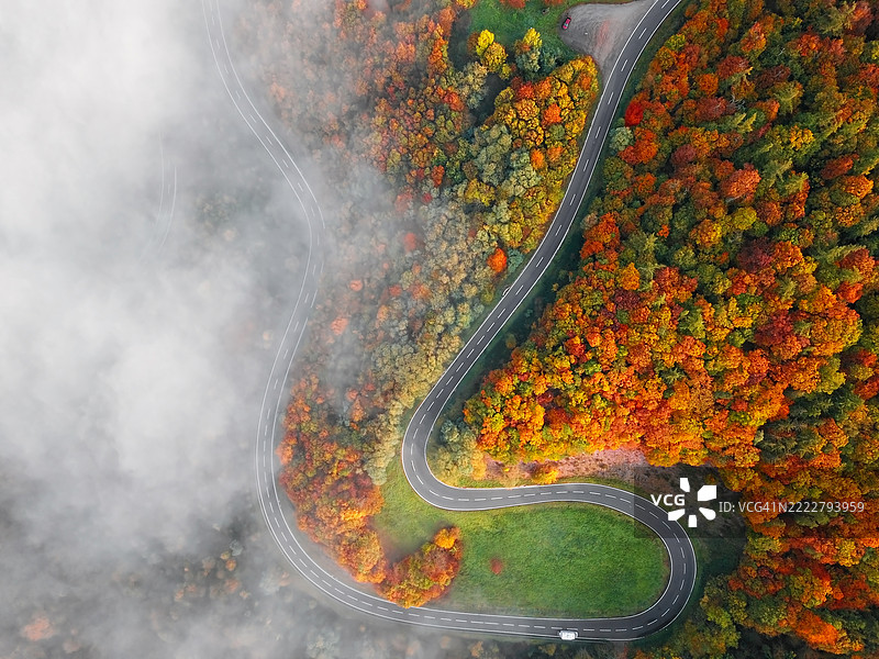 秋季森林中被晨雾笼罩的蜿蜒山路的俯瞰视图。德国摩泽尔谷。图片素材