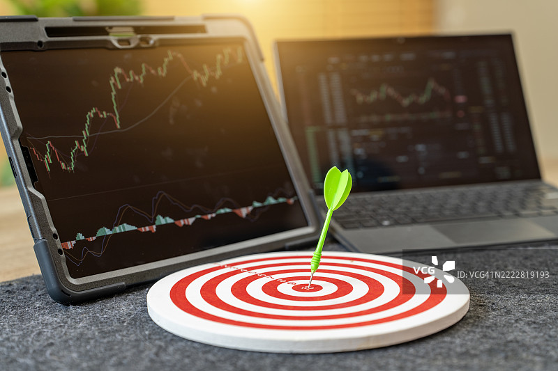 飞镖击中靶心，数字设备上显示股票图表图片素材