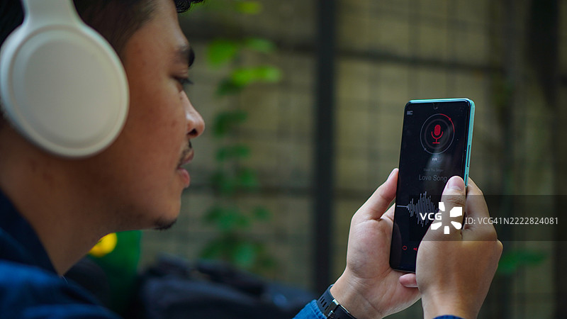 亚洲男子在手机上选择音乐图片素材