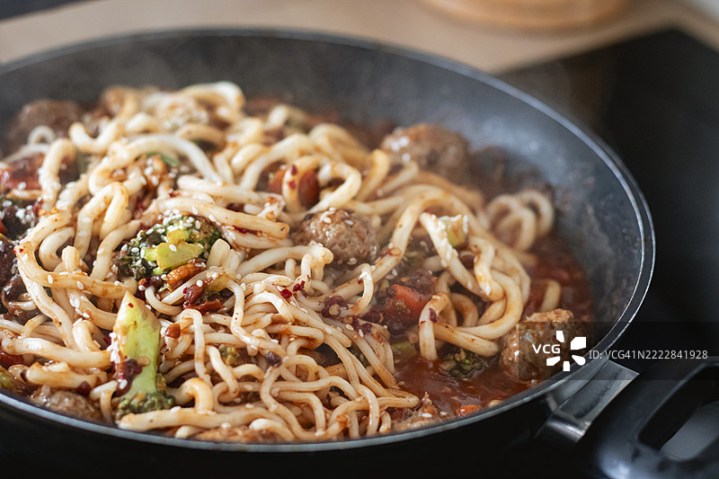 健康的蔬菜面条在炉子上的平底锅中烹饪，低角度特写视图图片素材