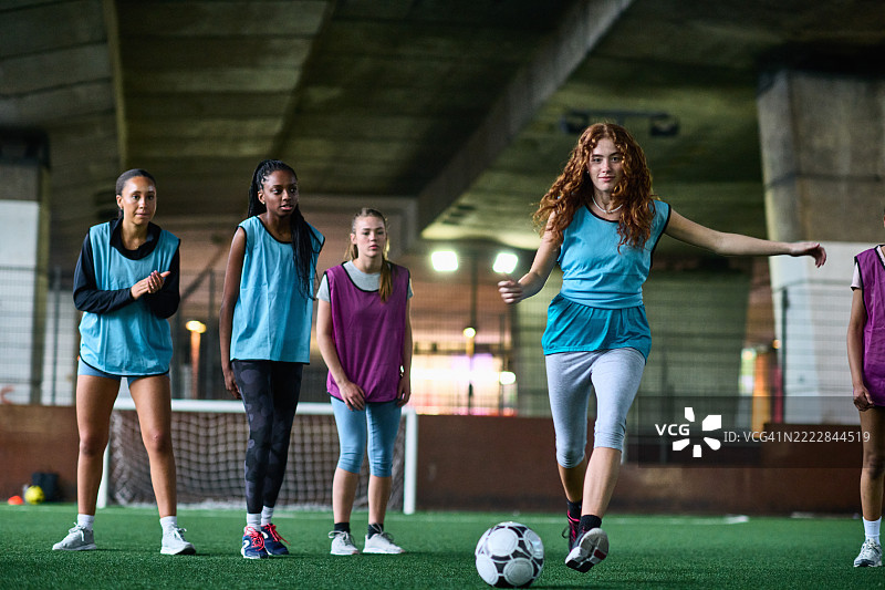 女足球员正在罚任意球，队友们在旁观看图片素材