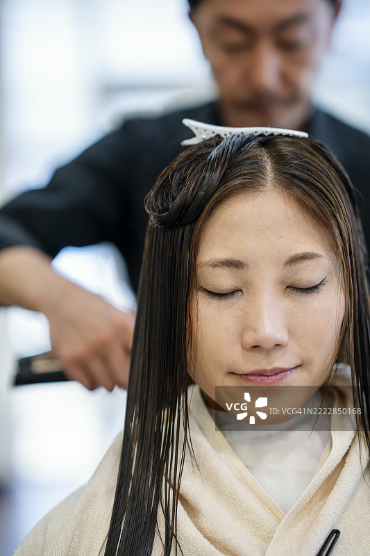 中年女性在美容院进行头发拉直的特写镜头图片素材