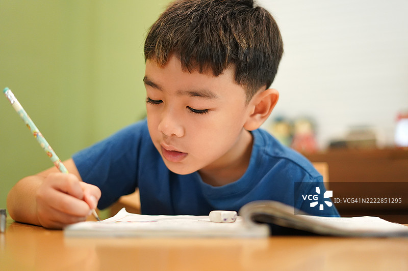 亚洲男孩正在桌子上做作业。图片素材