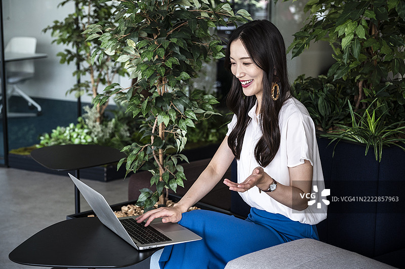 亚洲女性在绿色办公室中通过笔记本电脑进行在线会议。图片素材