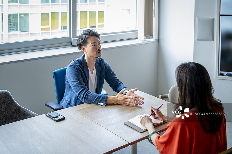 现代办公室环境中的日本求职面试，男性候选人自信地发言图片素材