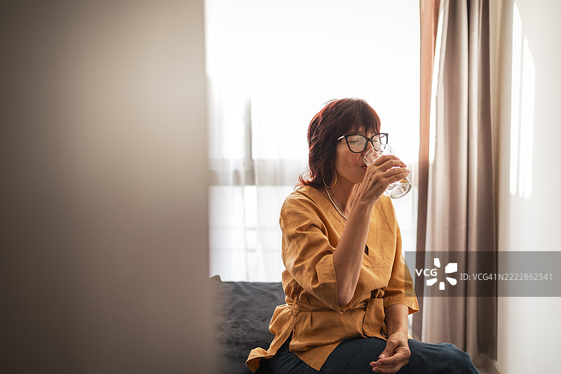 穿着休闲服的女人坐在窗边喝水图片素材