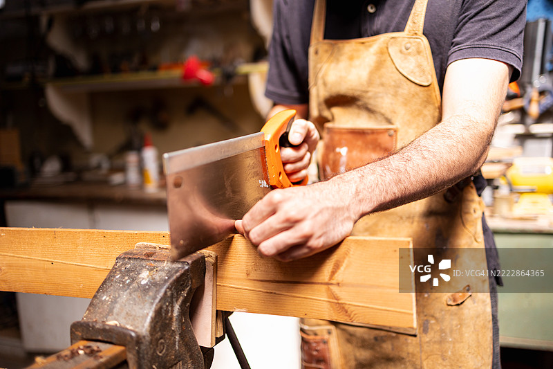 木匠在可持续的工作坊环境中使用手锯切割木材图片素材