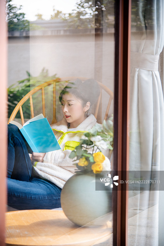 女人在窗后阅读一本书图片素材