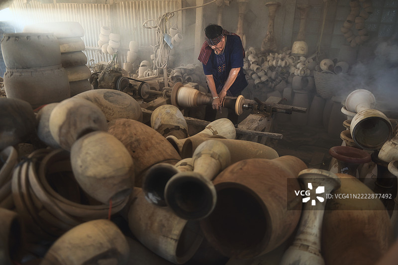 泰国工坊中男性陶艺家正在制作陶土罐的特写镜头图片素材