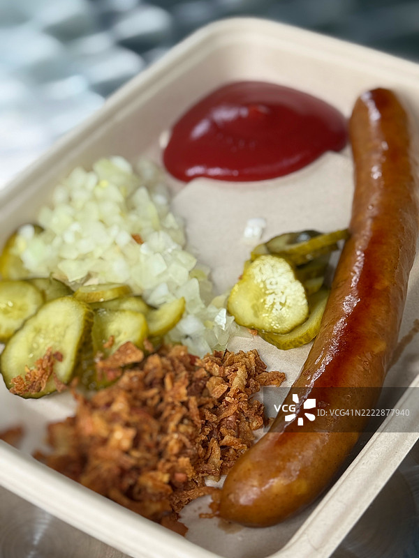 传统丹麦热狗香肠特写，配有番茄酱、生洋葱、炸洋葱和腌黄瓜图片素材