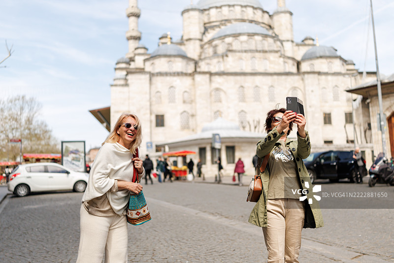 女性朋友在阳光明媚的日子里游览伊斯坦布尔时用手机自拍图片素材