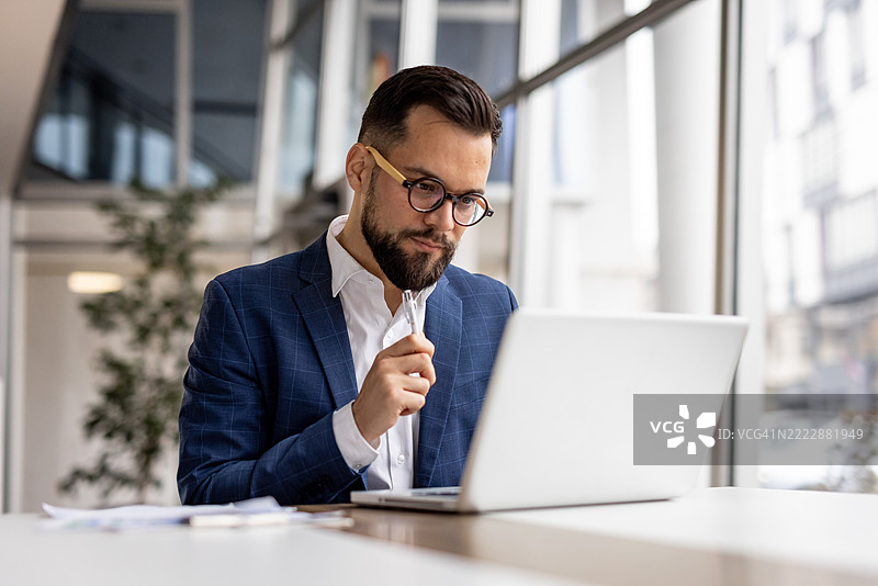 商人在现代办公室使用笔记本电脑工作图片素材