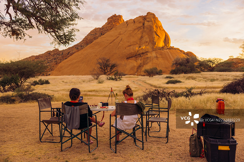 女孩们在户外享受晚餐，背景是纳米比亚斯皮茨科普山的壮丽景色图片素材