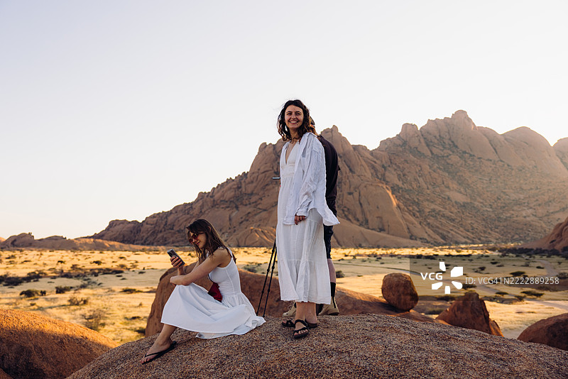 两个快乐的女孩在纳米比亚的壮丽斯皮茨科普山景观中欣赏日出图片素材