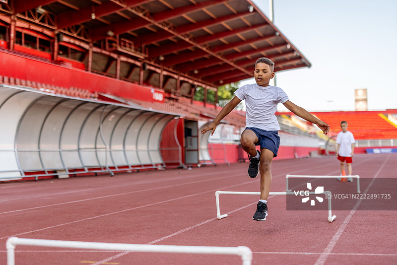 年轻运动员在体育场的跑道上练习跨栏图片素材