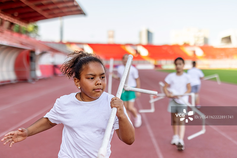 一群孩子在田径场上参加跨栏训练图片素材