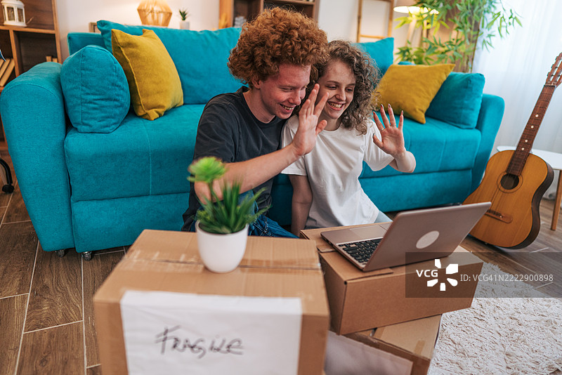 年轻情侣在搬入新家后视频通话朋友图片素材