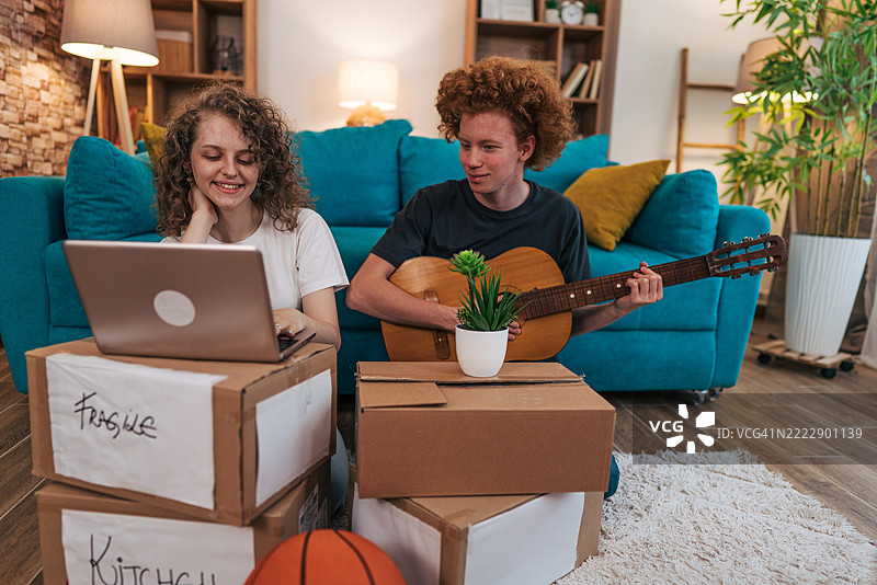 年轻人在新家 unpacking 和弹吉他图片素材