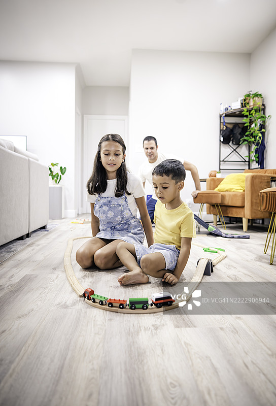 快乐的多种族兄妹在家中与爸爸一起在家庭客厅玩玩具图片素材