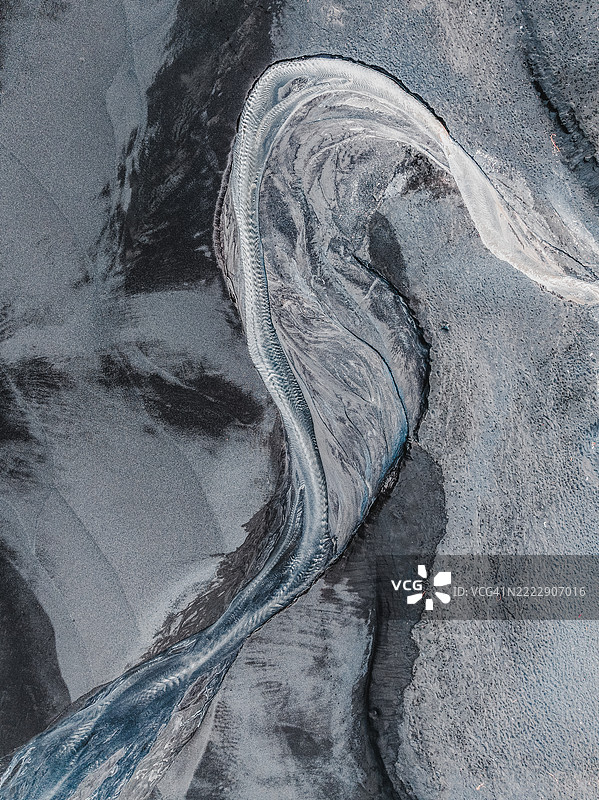 一条水流形成S形，流经巴厘岛印度尼西亚的黑沙滩，从上方拍摄。图片素材