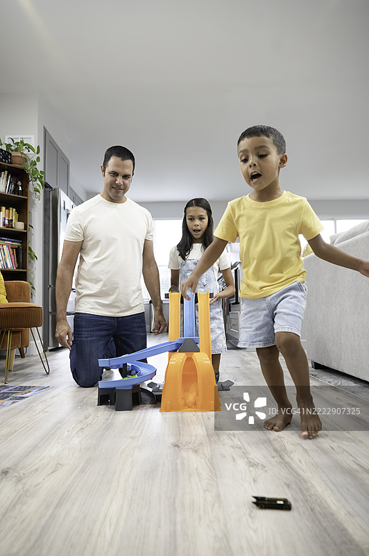 快乐的多种族兄妹在家中与爸爸一起在家庭客厅玩玩具图片素材