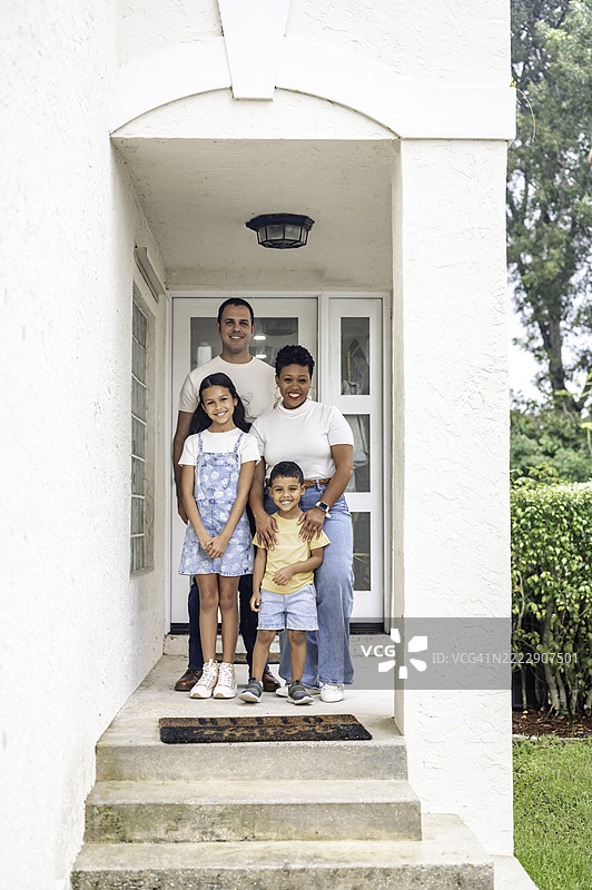 多种族的黑人和拉丁裔家庭，父母和两个孩子在家中面向镜头，幸福地合影。图片素材