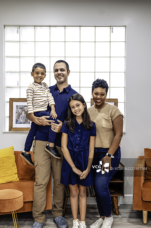 多种族的黑人和拉丁裔家庭，父母和两个孩子在家中面向镜头，幸福地合影。图片素材