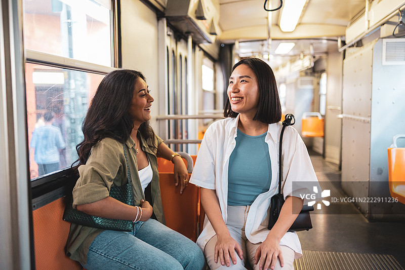 两位年轻女性在米兰地铁上交谈并微笑图片素材
