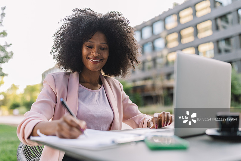 微笑的女性在户外使用笔记本电脑，显得很放松图片素材