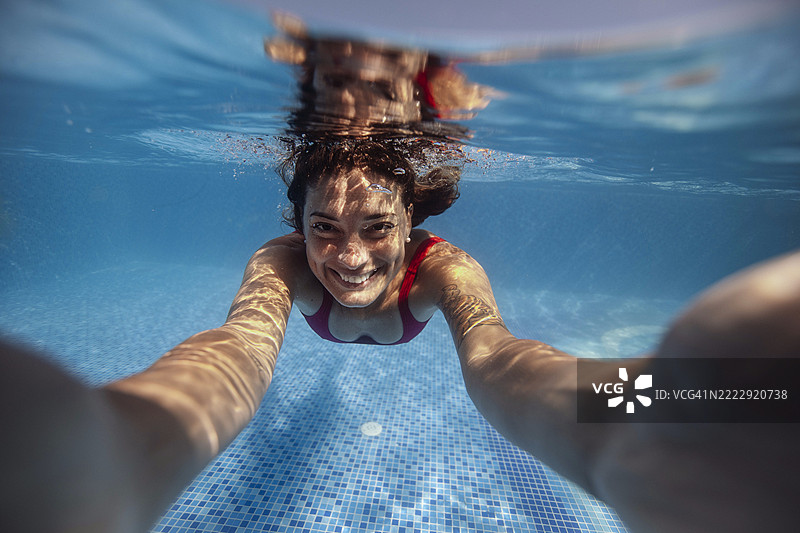 微笑的女性在泳池中潜水图片素材
