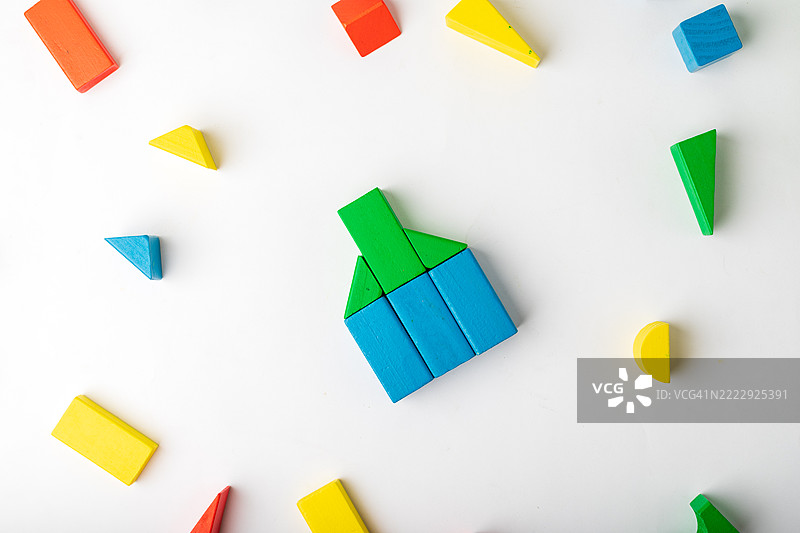 用木块搭建的房子，周围散落着各种形状图片素材