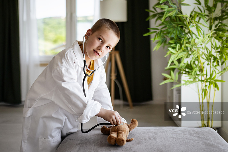 小男孩在客厅里和他的泰迪熊玩医生游戏图片素材