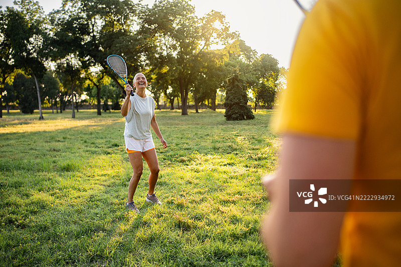 一对恩爱情侣在公园里享受着热闹的羽毛球比赛图片素材