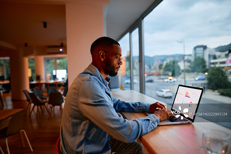 专注的商人在现代办公室分析笔记本电脑上的图表图片素材