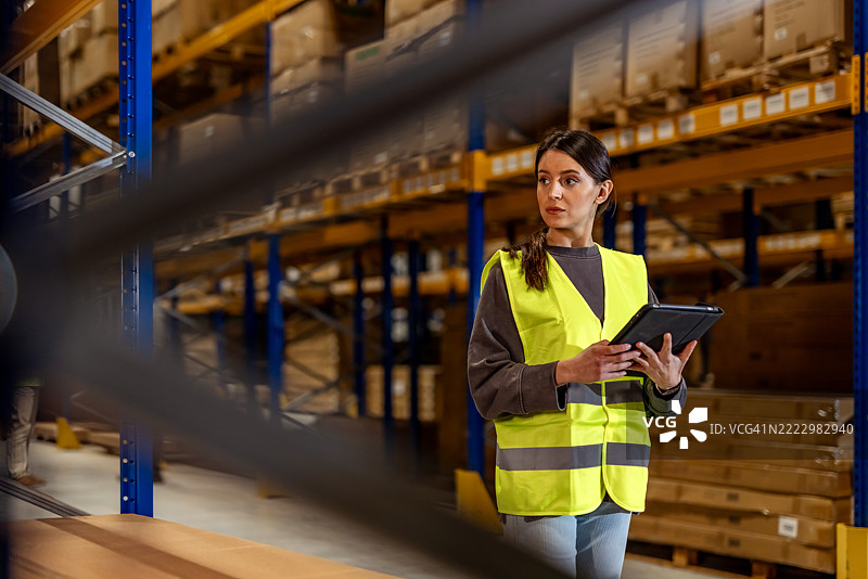 女性工作人员在仓储设施中使用平板电脑检查仓库库存图片素材