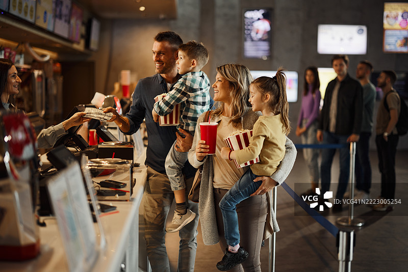 快乐的家庭在电影院购买电影票。图片素材