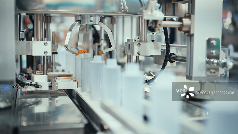 制药或化妆品生产线，配有小塑料瓶的自动分配器 | 现代工业包装机中的精密液体灌装系统图片素材