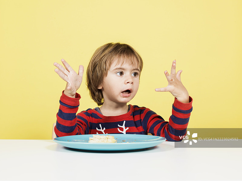 孩子在桌子旁坐着，惊讶地看着食物图片素材