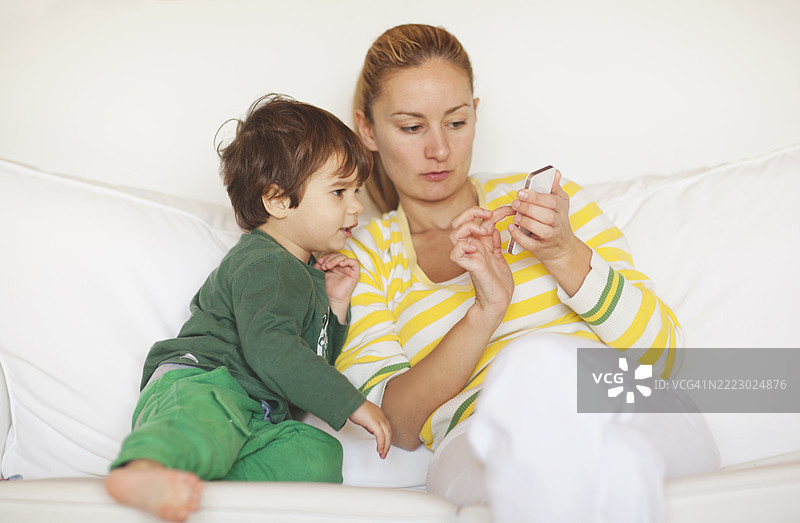 母亲和孩子在沙发上一起享受看手机的时光图片素材