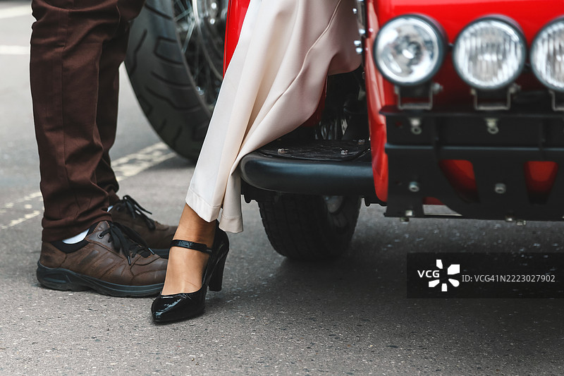 优雅的成年女性穿着方跟鞋，从复古摩托车侧车上下来图片素材